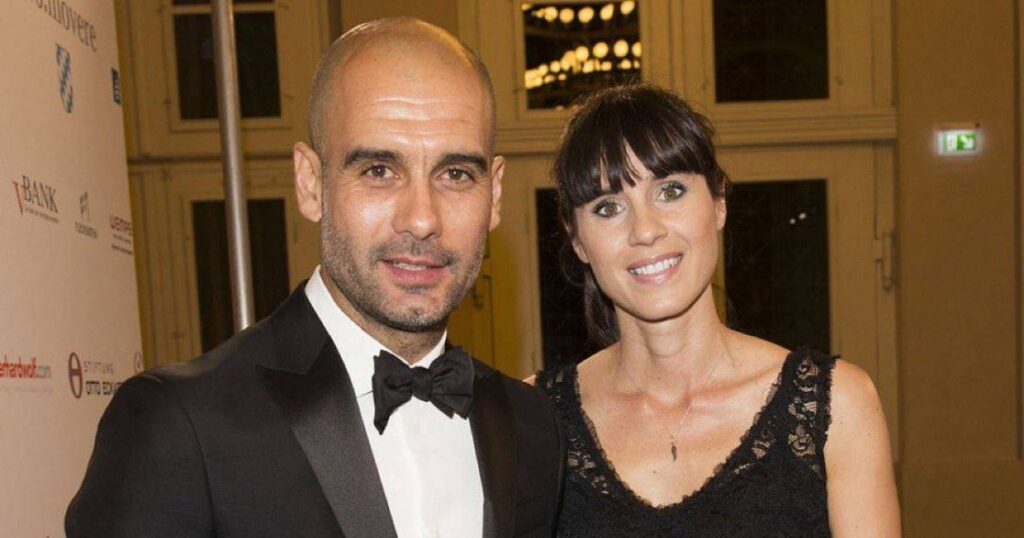 A man and woman in formal attire stand together, smiling for a photo in a well-lit setting.