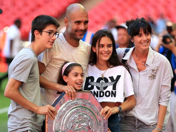 A group of five, including a man, two women, and two children, joyfully display a trophy, symbolizing their shared success.