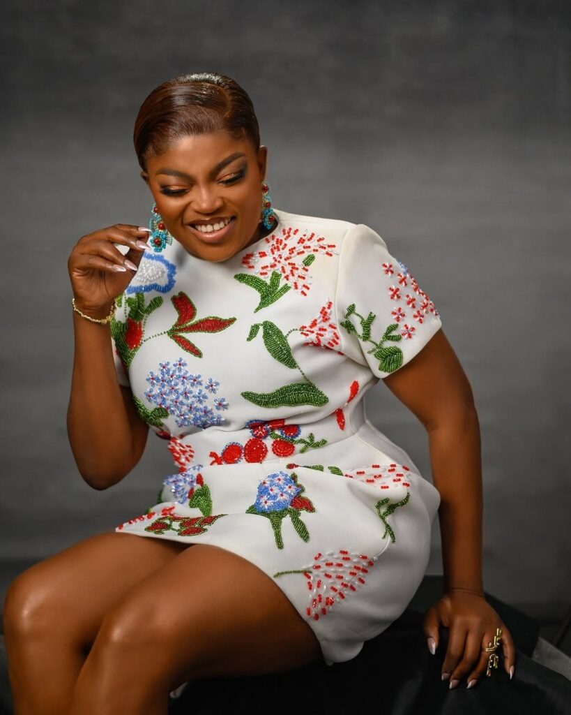 Funlke Akindele sitting in a floral embroidered gown