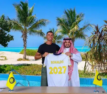 Cristiano Ronaldo holds an Al Nassr jersey marked '2027' next to club chairman Abdullah Almajid after signing contract extension.